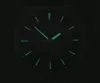 A close-up view of a watch face in the dark, with luminous hands and hour markers glowing green. Anteprima dell’immagine prodotto