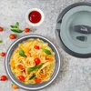A plate of pasta with tomatoes and basil next to a food container. Náhled obrázku produktu