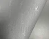 A close-up, angled view of a roll of wallpaper with a perforated pattern and faint text. Podgląd zdjęcia produktu