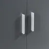A close-up view of two white handles on a dark gray cabinet or furniture. Produktbild-Vorschau
