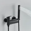 A black wall-mounted bathtub faucet with a handheld showerhead spraying water. Produktbild-Vorschau