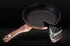 A frying pan with a cutaway showing its layered construction, presented against a dark background. Voir les images du produit