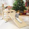 Two young children are playing on a wooden climbing set in a room decorated for Christmas. Podgląd zdjęcia produktu