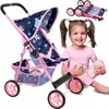 A young girl is sitting on the floor next to a doll stroller. The stroller is pink and navy blue with a butterfly pattern. The girl is smiling and looking at the camera. Produktbild-Vorschau