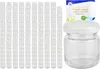 A large group of small glass jars are stacked in columns on the left, with a single jar and a product package on the right. Produktbild-Vorschau