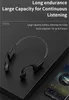 A pair of black and gray bone conduction headphones are placed on a dark surface next to a smartphone displaying music. Podgląd zdjęcia produktu