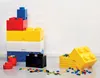 A collection of LEGO-style storage bricks in various colors, stacked and arranged on a light gray surface against a white wall. Voir les images du produit