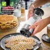 A person is using a powder sugar dispenser to dust waffles. Podgląd zdjęcia produktu