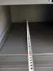 A close-up view of a measuring tape placed inside a gray cabinet or shelf. Produktbild-Vorschau