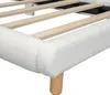 A close-up view of the corner of a white upholstered bed frame with wooden slats and a wooden leg. Produktbild-Vorschau