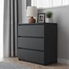 A dark gray dresser with three drawers is shown in a room with gray walls and curtains. Náhled obrázku produktu