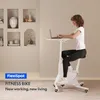 A woman is using a white fitness bike with a laptop on its attached desk in a modern, minimalist room. Voir les images du produit