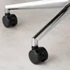 Close-up view of the casters (wheels) and metal legs of an office chair on a light gray floor. Produktbild-Vorschau