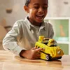 A young boy is happily playing with a yellow toy vehicle on a wooden table. Náhled obrázku produktu