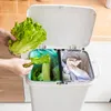 A person is shown discarding lettuce into a dual-compartment trash can in a kitchen. Produktbild-Vorschau