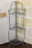A metal corner shelf unit is shown against a stone wall. Podgląd zdjęcia produktu