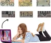 A young girl is lying on the floor, looking at a laptop with a cartoon image on the screen. Above her are several pixelated images, possibly from a game or an old electronic device. Voir les images du produit