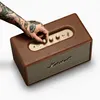 A hand with tattoos is adjusting the knobs on a brown Marshall speaker. Produktbild-Vorschau