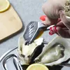 A person is using a lemon squeezer to add lemon juice to oysters. Voir les images du produit