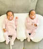 Two babies lying on a pillow on a couch. Voir les images du produit