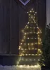 A Christmas tree silhouette made of lights is attached to a wooden wall, with some snow on the ground. Podgląd zdjęcia produktu