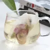 A close-up shot of a tea bag with rosebuds steeping in a clear glass mug of tea. Anteprima dell’immagine prodotto