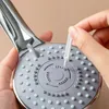 A close-up shot of a person cleaning a shower head with a small tool. Voir les images du produit