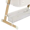 A close-up view of the lower section of a baby crib or bassinet, showing the wooden legs and a storage basket. Produktbild-Vorschau