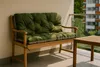 A green cushion on a wooden bench on a balcony with a building in the background. Produktbild-Vorschau