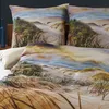 A close-up view of a bed with bedding featuring a beach and dune landscape print. Produktbild-Vorschau