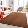 A living room scene with a sofa, armchair, and a large brown rug. Anteprima dell’immagine prodotto