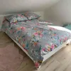 A bed with floral patterned bedding in a room with a sloped ceiling. Produktbild-Vorschau