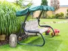 A garden swing with cushions is set up on a green lawn, surrounded by plants and flowers. Náhled obrázku produktu