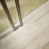 A close-up view of two metal rods standing on a light-colored wooden floor, with a textured yellow wall in the background. Produktbild-Vorschau