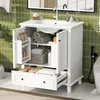 A white bathroom vanity with a ceramic sink, open doors revealing shelves with towels and bottles, and a partially open drawer. The background features green tiled walls. Náhled obrázku produktu