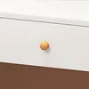 A close-up of a white drawer with a wooden knob and a brown surface below. Podgląd zdjęcia produktu
