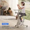 A woman is using a fitness bike with a desk attachment while holding a phone. Podgląd zdjęcia produktu