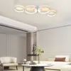 A modern living room with a white sectional sofa, a cream armchair, and a marble coffee table. A contemporary white ring chandelier hangs from the ceiling. Voir les images du produit