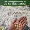 A hand holding small pasta shells with flour sprinkled on a dark surface, and German text written in the flour. Podgląd zdjęcia produktu