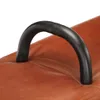A close-up of a black handle on a brown leather surface. Voir les images du produit
