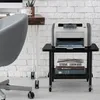 A printer and books are on a small rolling cart next to a desk and chair. Produktbild-Vorschau