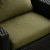 Close-up of a green cushion on a dark rattan chair, showing water droplets on the fabric. Produktbild-Vorschau
