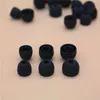 A collection of black silicone earbud tips arranged on a light beige surface. Produktbild-Vorschau