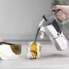 A hand is pouring coffee from a moka pot into a glass mug with a scoop of ice cream inside. Produktbild-Vorschau