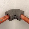 A close-up shot of a gray foam pipe insulation fitting on copper pipes. Produktbild-Vorschau