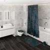 A modern bathroom with marble tiles, a white vanity with a sink, a toilet, a bathtub with a floral shower curtain, and dark wood flooring. Produktbild-Vorschau