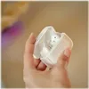 A hand holding a white charging case with white earbuds inside. Anteprima dell’immagine prodotto