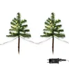 Two small, artificial Christmas trees with warm white LED lights, each on a stake, and a power adapter are shown against a white background. Produktbild-Vorschau