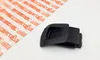A black plastic part is placed on a white surface next to a sheet of paper with orange text. Produktbild-Vorschau
