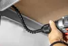A hand holding a drill with a flexible bit extension attached, working in a tight space under a shelf. Produktbild-Vorschau